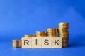 Business, Money and Risk Management Concept. Closeup of English letter wooden block with stack of coins on blue background Royalty Free Stock Photo