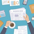 Business news. Businessman holding a newspaper and coffee cup on the desktop.