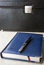 Business notebook and pen  on the table in front of the briefcase Royalty Free Stock Photo