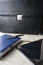 Business notebook, pen and tablet on the table in front of the briefcase Royalty Free Stock Photo