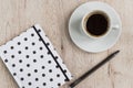 Business and office concept - black and white polka dot cover notebook, pen and cup of black coffee on wooden table. top view Royalty Free Stock Photo