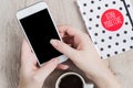 Business and office concept - woman hands holding white smartwhone next to the black and white polka dot cover notebook and cup of Royalty Free Stock Photo