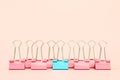 Blue binder clip standing out of pink binder clips on pink background with copy space Royalty Free Stock Photo