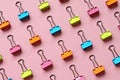 Lines of multi colored binder clips on pink background Royalty Free Stock Photo