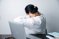 A business office worker is an asian woman is sitting in front of the laptop computer. A businesswoman stressing her body part Royalty Free Stock Photo