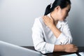 A business office worker is an asian woman is sitting in front of the laptop computer. A businesswoman stressing her body part Royalty Free Stock Photo