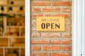 Business open and welcome wooden sign board at bricks wall beside the door