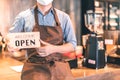 Business owner attractive young Asian man in apron hanging we`re open sign on front door  welcoming clients to new cafe. Happy Royalty Free Stock Photo