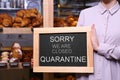 Business owner holding sign with text SORRY WE ARE CLOSED QUARANTINE in bakery Royalty Free Stock Photo