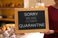Business owner holding sign with text SORRY WE ARE CLOSED QUARANTINE in bakery Royalty Free Stock Photo
