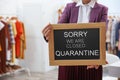 Business owner holding sign with text SORRY WE ARE CLOSED QUARANTINE in boutique Royalty Free Stock Photo