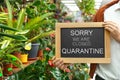 Business owner holding sign with text SORRY WE ARE CLOSED QUARANTINE in flower shop Royalty Free Stock Photo