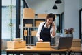 Business owner talking on mobile phone and taking order. Female asian entrepreneur working at home office confirming the Royalty Free Stock Photo