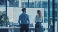 Business partners analyzing interactive display with diagrams and data graphs inside contemporary corporate workspace