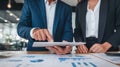 Business partners collaborating on data analysis, using a tablet and reviewing charts during a professional meeting in an office Royalty Free Stock Photo