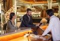 Business partners or colleagues doing check in at the hotel. Young couple and receptionist at counter in hotel