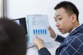 Business partners concept a young businessman pointing at profit summary of the recent month showing in document forms