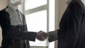 Business partners confirming deal with firm handshake, teamwork, partnership