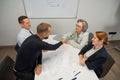 Business partners shake hands. Four business people are negotiating in the conference room.