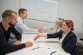 Business partners shake hands. Four business people are negotiating in the conference room.