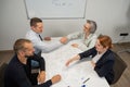 Business partners shake hands. Four business people are negotiating in the conference room.