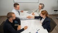 Business partners shake hands. Four business people are negotiating in the conference room.