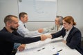 Business partners shake hands. Four business people are negotiating in the conference room.