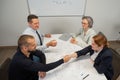 Business partners shake hands. Four business people are negotiating in the conference room.