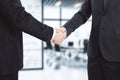 Business partners shake hands in modern conference room