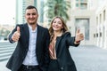 business, partnership, success, gesture and people concept. Smiling businessman and businesswoman showing thumbs up over office Royalty Free Stock Photo