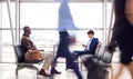 Business Passengers Sitting In Busy Airport Departure Lounge Using Mobile Phones