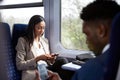 Business Passengers Sitting In Train Commuting To Work Looking At Mobile Phones