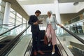 Business people with bags and digital tablet standing on escalator in a modern office Royalty Free Stock Photo