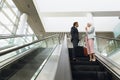 Business people with bags talking with each other on escalator in a modern office Royalty Free Stock Photo