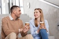 Man and woman with coffee talking at office stairs Royalty Free Stock Photo