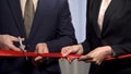 Business people cutting red ribbon with scissors, start-up and collaboration