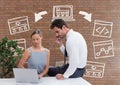 Business people at a desk looking at a computer against brick wall with graphics Royalty Free Stock Photo