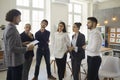 Young man shares his business ideas with colleagues standing next to him in a modern bright office. Royalty Free Stock Photo
