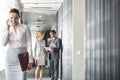 Business people discussing in corridor with colleague using cell phone in foreground Royalty Free Stock Photo