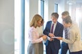 Business people discussing over document while standing in corridor at office Royalty Free Stock Photo