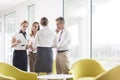 Business people discussing over documents in office lobby