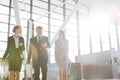 Business people discussing plans while walking with their luggage in airport Royalty Free Stock Photo