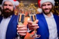 Business people drink champagne at party. Colleagues celebrate new year. Men formal suits and santa hats hold champagne