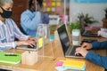 Business people with face masks inside coworking office behind safety plexiglas - Focus on right man hands