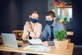 Business people with face masks working together on laptop in modern coworking office Royalty Free Stock Photo