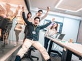 Business people having fun riding on chairs in office