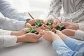 Business people holding green seedlings with soil on light table Royalty Free Stock Photo