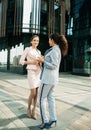 two office workers standing together outdors near modern business building. Positive emotions. Royalty Free Stock Photo