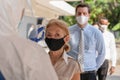 Business people line up for fever checking with digital temperature scanning device before enter office building for coronavirus