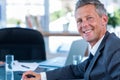Middle-aged man in dark suit working on laptop at desk with papers and water glass Royalty Free Stock Photo
